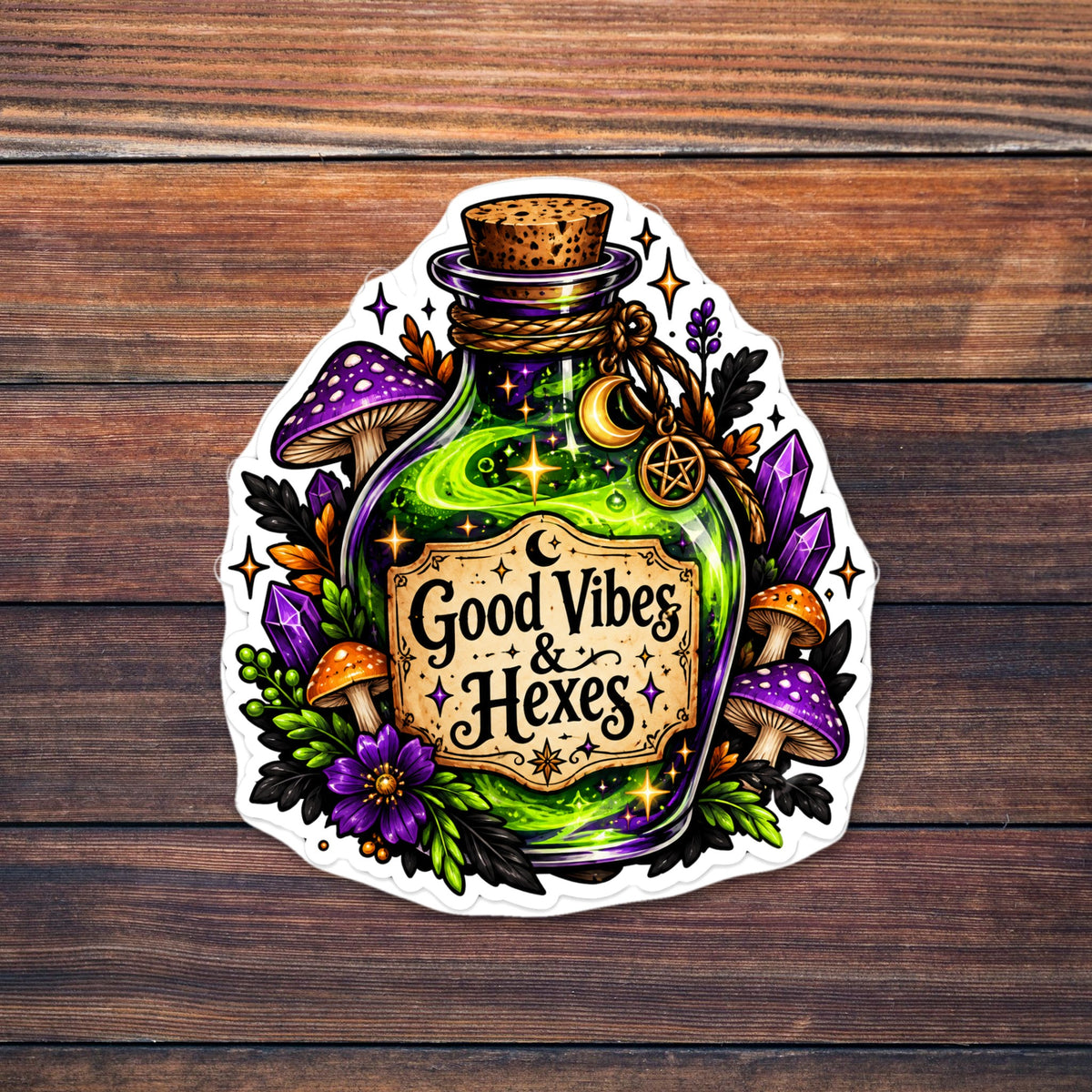 Corked glass potion bottle with swirling glowing green liquid, a parchment label, and crescent moon and pentagram charms tied with twine, surrounded by purple and orange spotted mushrooms, amethyst crystals, leaves, berries and a purple flower, with the text Good Vibes & Hexes. shown on a wooden table