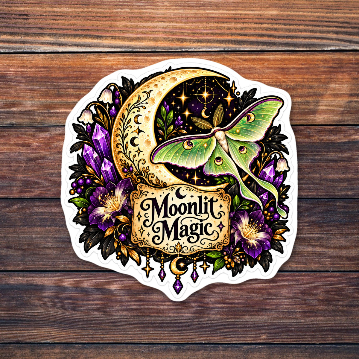 Die-cut sticker of a pale green luna moth over a golden crescent moon and starry night sky, surrounded by purple amethyst crystals, purple and white bell flowers, dark leaves and gold filigree, with a parchment label reading Moonlit Magic. shown on a wooden table